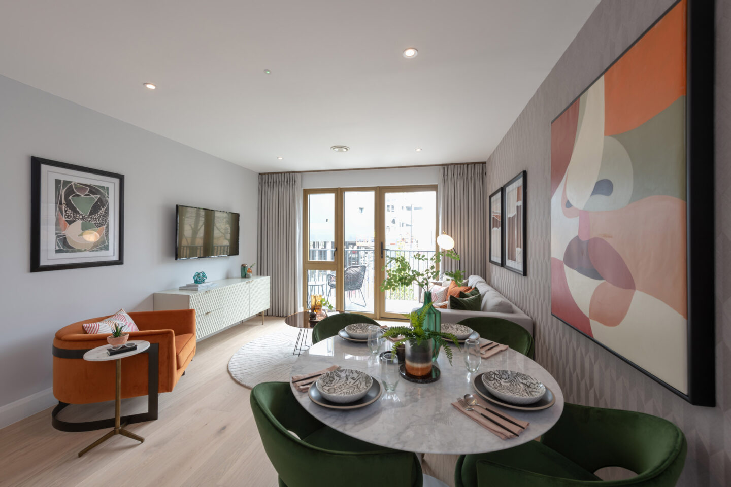 Modern living and dining area with large windows, stylish furniture, abstract wall art, and a set dining table in a bright, open-plan flat.